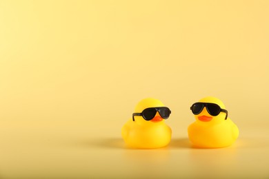 Photo of Cute rubber ducks on yellow background, space for text