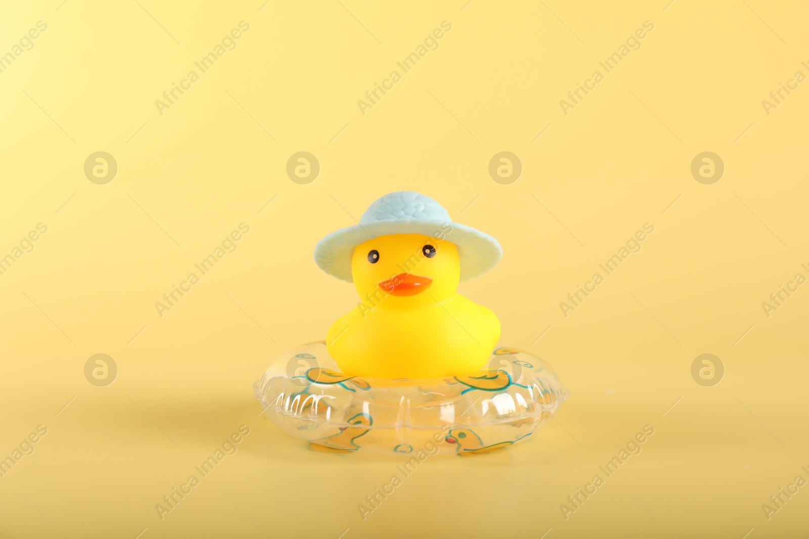 Cute rubber duck in hat and inflatable ring on yellow background Photo of Cute rubber duck in hat and inflatable ring on yellow background