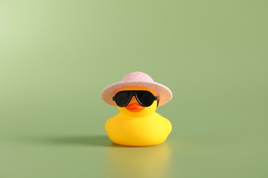 Photo of Cute rubber duck in sunglasses and hat on green background