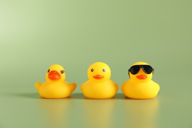 Photo of Three cute rubber ducks on green background