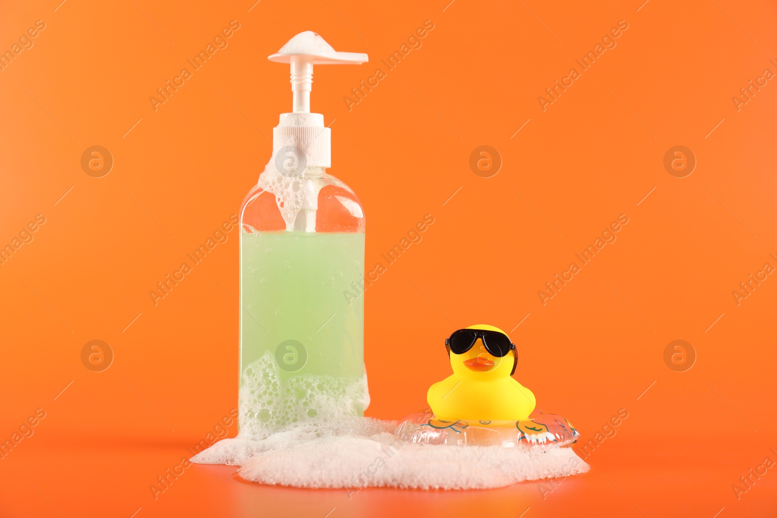 Cute rubber duck, foam, inflatable ring and bottle of cosmetic product Photo of Cute rubber duck, foam, inflatable ring and bottle of cosmetic product