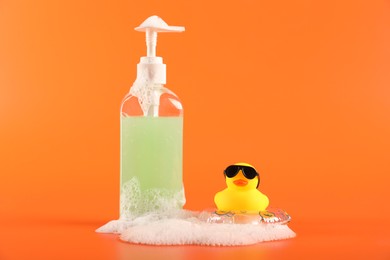 Photo of Cute rubber duck, foam, inflatable ring and bottle of cosmetic product