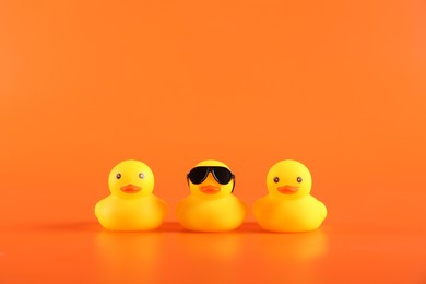Photo of Three cute rubber ducks on orange background