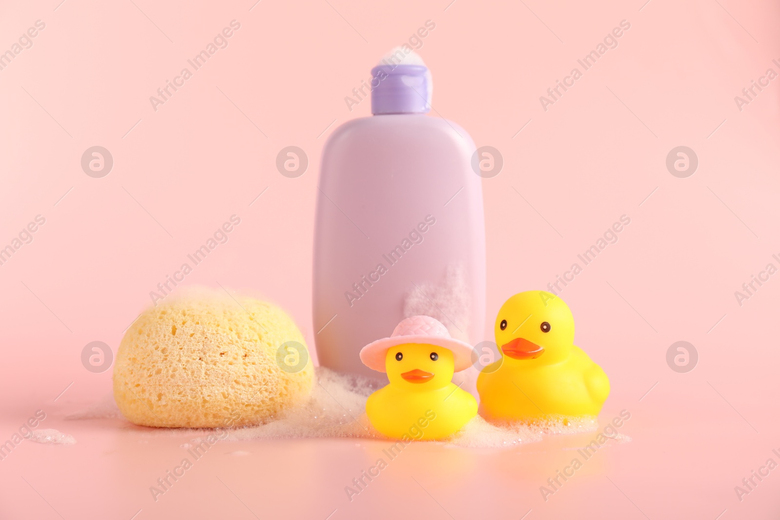 Cute rubber ducks, sponge and bottle of shampoo on pink background Photo of Cute rubber ducks, sponge and bottle of shampoo on pink background