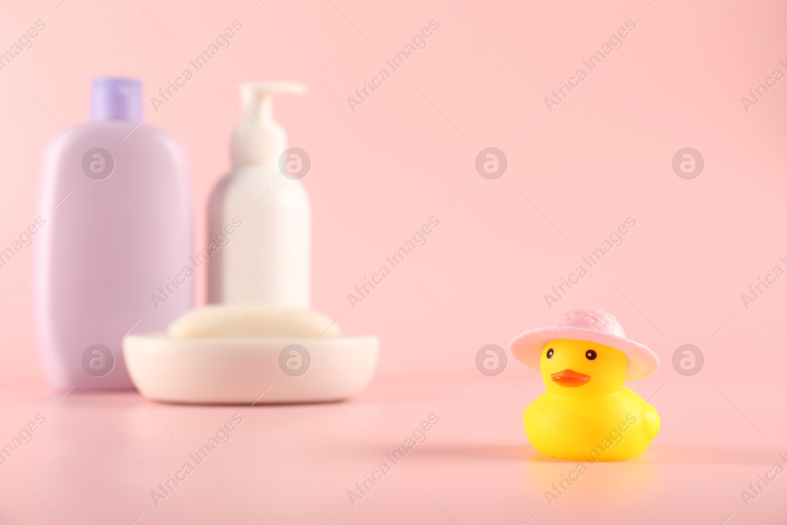 Cute rubber duck in hat, soap and bottles of cosmetic products on pink background Photo of Cute rubber duck in hat, soap and bottles of cosmetic products on pink background