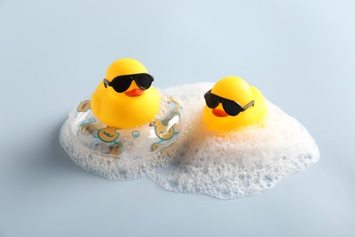 Photo of Cute rubber ducks, foam and inflatable ring on white background