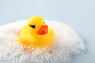 Photo of Cute rubber duck and foam on white background, closeup. Space for text