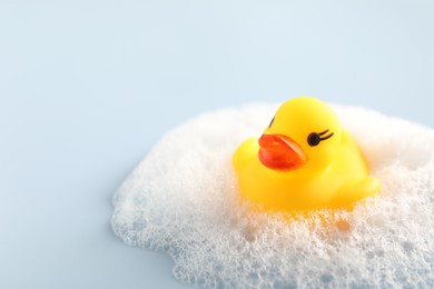Photo of Cute rubber duck and foam on white background, closeup. Space for text