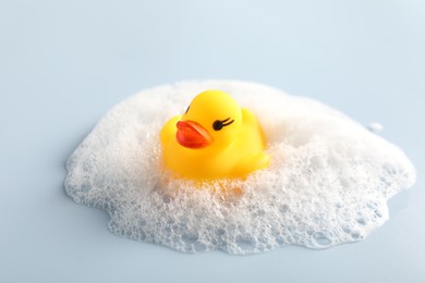 Photo of Cute rubber duck and foam on white background, closeup