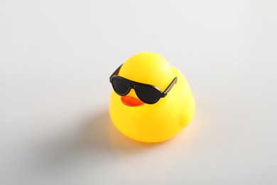 Photo of Cute rubber duck in sunglasses on white background, closeup
