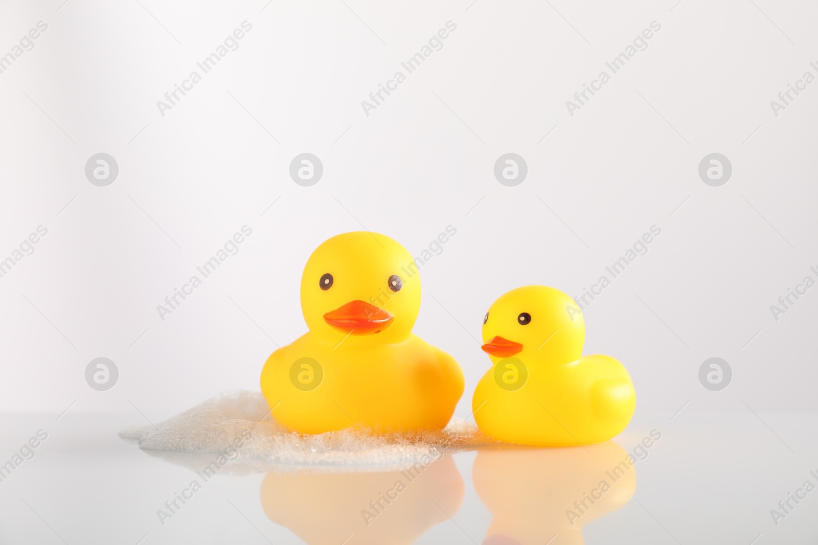 Cute rubber ducks and foam on white background Photo of Cute rubber ducks and foam on white background