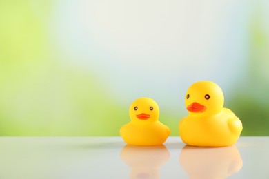 Photo of Two cute rubber ducks on table against blurred background, space for text