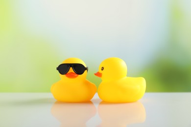 Photo of Two cute rubber ducks on table against blurred background