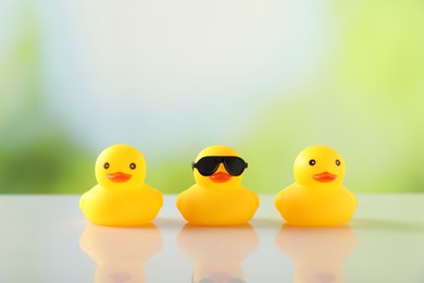 Photo of Three cute rubber ducks on table against blurred background