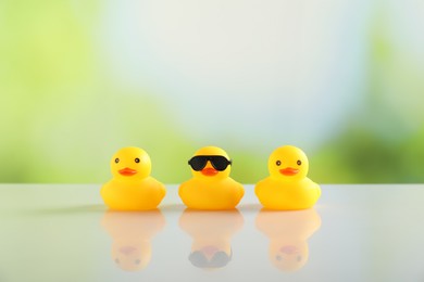 Photo of Three cute rubber ducks on table against blurred background
