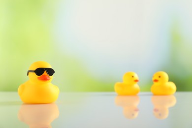 Photo of Cute rubber ducks on table against blurred background, selective focus