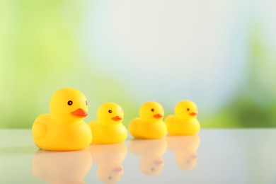 Photo of Cute rubber ducks on table against blurred background, closeup. Space for text