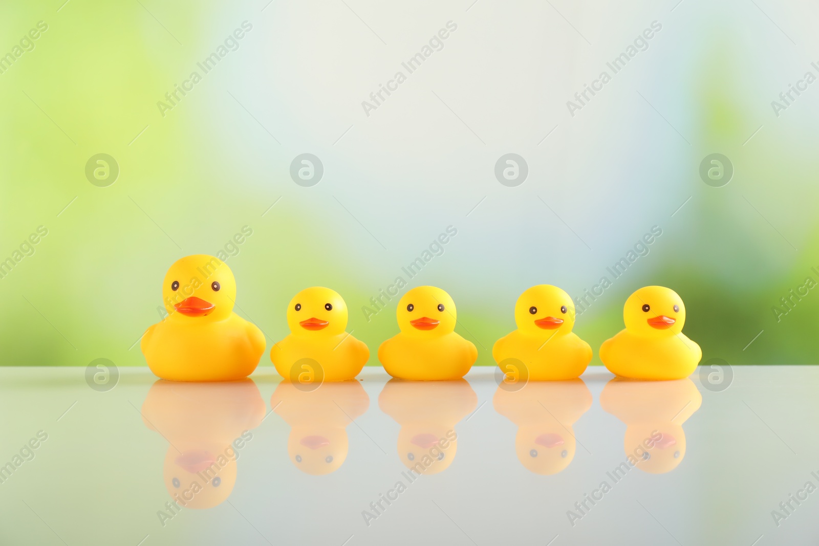 Cute rubber ducks on table against blurred background Photo of Cute rubber ducks on table against blurred background