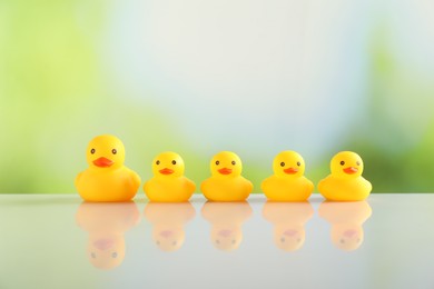 Photo of Cute rubber ducks on table against blurred background