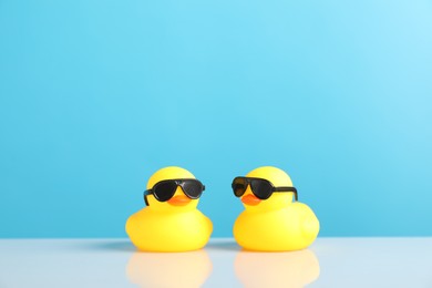 Photo of Two cute rubber ducks on table against light blue background