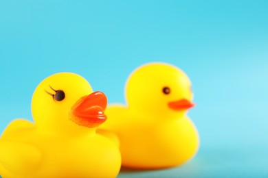 Photo of Two cute rubber ducks on light blue background, closeup