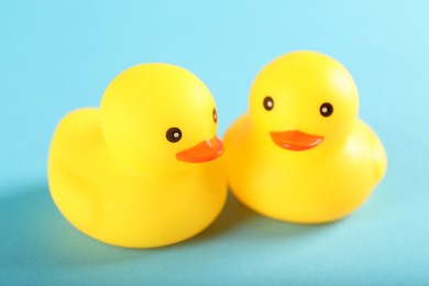 Photo of Two cute rubber ducks on light blue background, closeup
