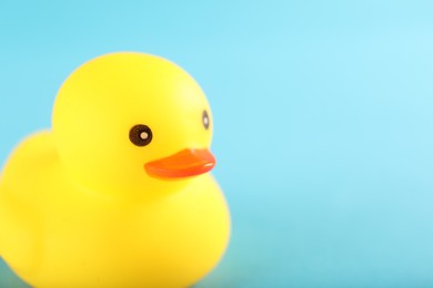 Photo of One cute rubber duck on light blue background, closeup. Space for text
