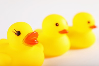 Photo of Three cute rubber ducks on white background, closeup. Space for text