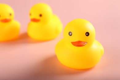Photo of Three cute rubber ducks on pink background, closeup