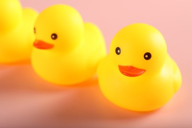 Photo of Three cute rubber ducks on pink background, closeup