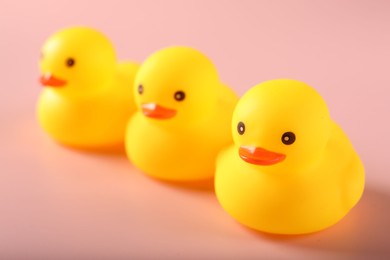 Photo of Three cute rubber ducks on pink background, closeup