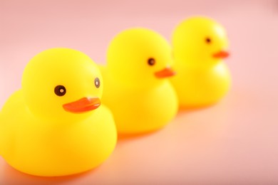 Photo of Three cute rubber ducks on pink background, closeup