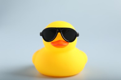 Photo of Cute rubber duck with sunglasses on white background, closeup