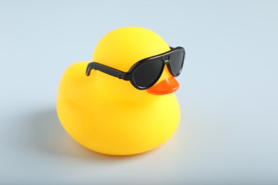 Photo of Cute rubber duck with sunglasses on white background, closeup