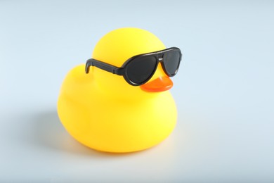 Photo of Cute rubber duck with sunglasses on white background, closeup