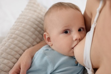 Photo of Mother breastfeeding her little baby indoors, closeup