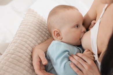 Photo of Mother breastfeeding her little baby on bed indoors, closeup
