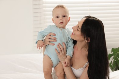 Photo of Smiling mother with her little baby on bed at home. Space for text