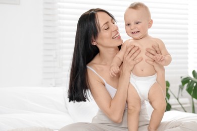 Photo of Smiling mother with her little baby on bed at home. Space for text