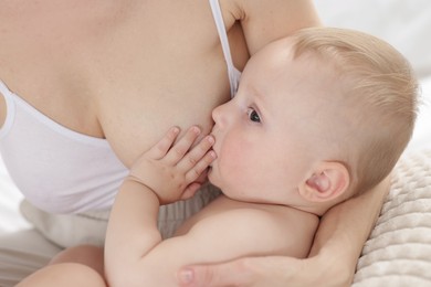 Photo of Mother breastfeeding her little baby indoors, closeup