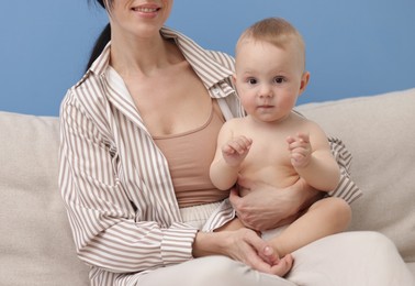 Photo of Smiling mother with her little baby on sofa indoors