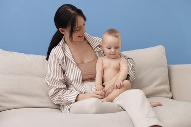 Photo of Smiling mother with her little baby on sofa indoors