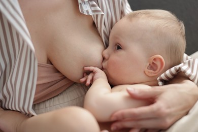 Photo of Mother breastfeeding her little baby indoors, closeup