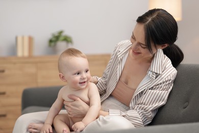 Photo of Smiling mother with her little baby on sofa indoors