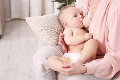 Photo of Mother breastfeeding her little baby indoors, closeup