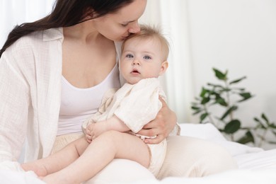 Photo of Mother kissing her little baby on bed at home