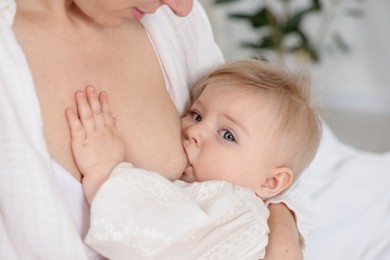 Photo of Mother breastfeeding her cute little baby indoors, closeup