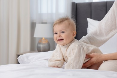 Photo of Cute little baby and mother on bed indoors, closeup