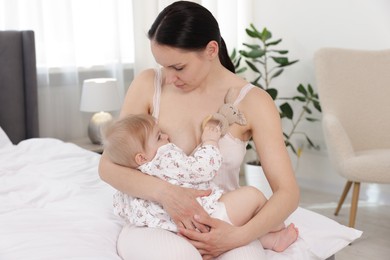 Photo of Mother breastfeeding her cute little baby on bed indoors
