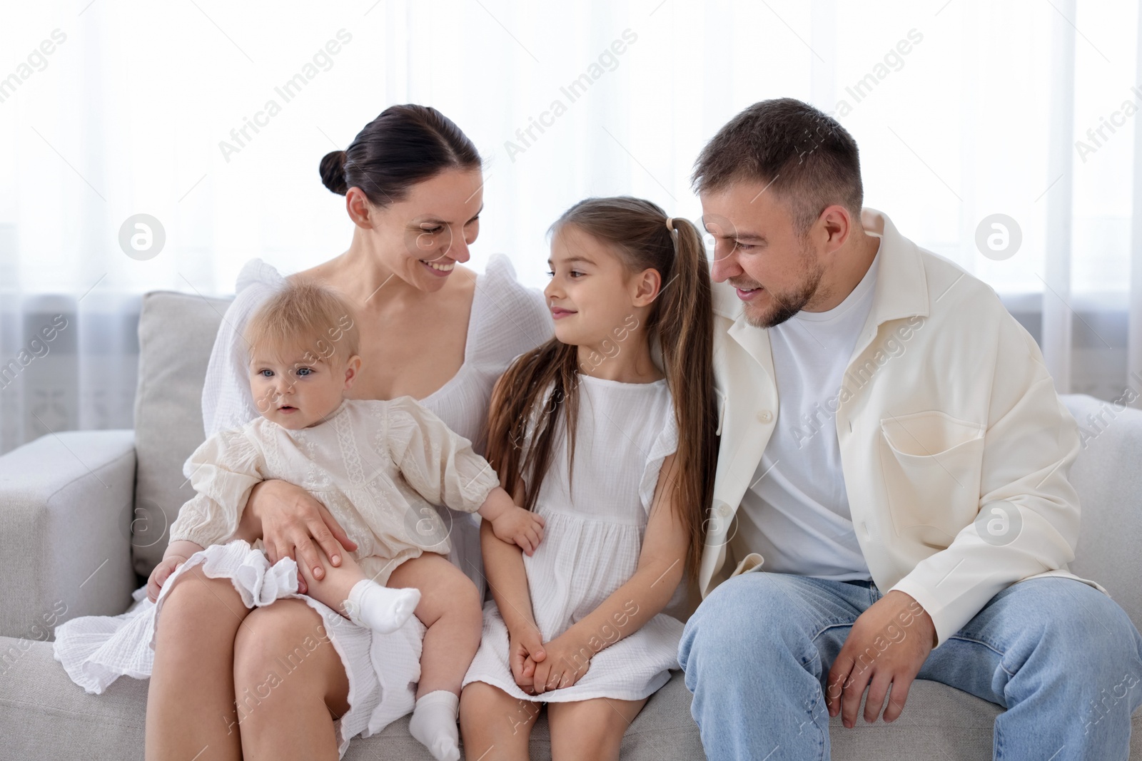 Happy parents and their kids together on sofa at home Photo of Happy parents and their kids together on sofa at home